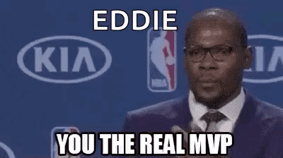 A Man In A Suit And Tie Is Giving A Speech At A Basketball Game . GIF