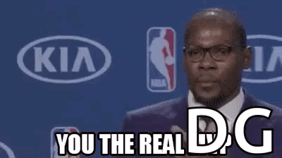 A Man In A Suit And Tie Is Giving A Speech At A Basketball Game . GIF