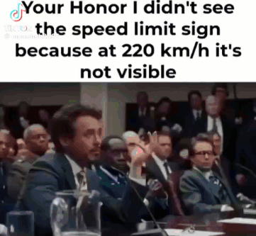 A Man In A Suit And Tie Is Giving A Speech In Front Of A Crowd Of People . GIF