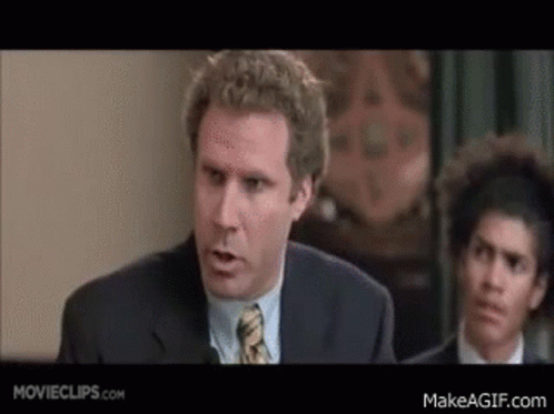 A Man In A Suit And Tie Is Giving A Speech In Front Of A Group Of People . GIF