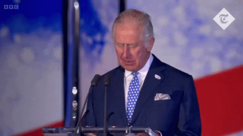 A Man In A Suit And Tie Is Giving A Speech In Front Of Microphones . GIF