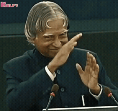 A Man In A Suit And Tie Is Giving A Speech In Front Of Microphones And Applauding . GIF