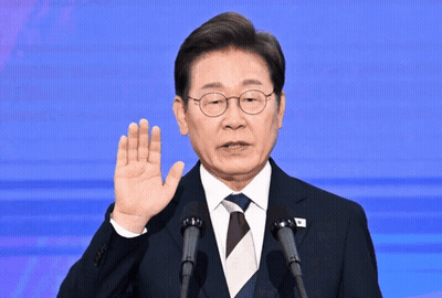 A Man In A Suit And Tie Is Giving A Speech In Front Of Two Microphones GIF