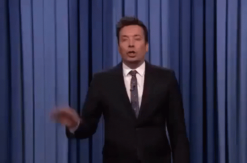 A Man In A Suit And Tie Is Giving A Speech On A Stage . GIF