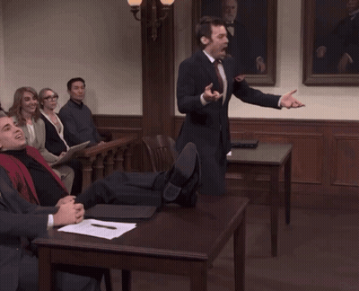 A Man In A Suit And Tie Is Giving A Speech To A Group Of People GIF