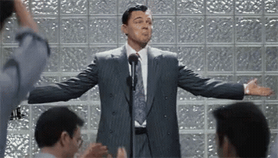A Man In A Suit And Tie Is Giving A Speech To A Group Of People . GIF