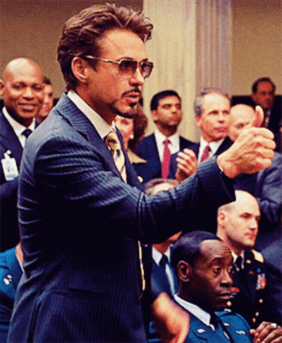 A Man In A Suit And Tie Is Giving A Thumbs Up In Front Of A Crowd GIF
