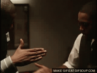 A Man In A Suit And Tie Is Giving Another Man A High Five GIF
