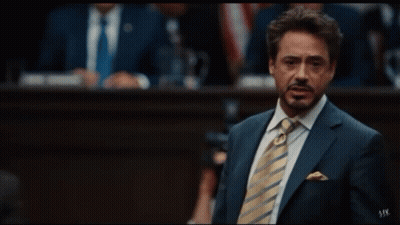 A Man In A Suit And Tie Is Giving The Peace Sign GIF