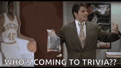 A Man In A Suit And Tie Is Holding A Bag Of Food In Front Of A Basketball Player . GIF