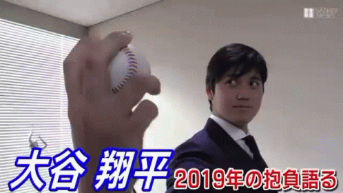A Man In A Suit And Tie Is Holding A Baseball In His Right Hand . GIF