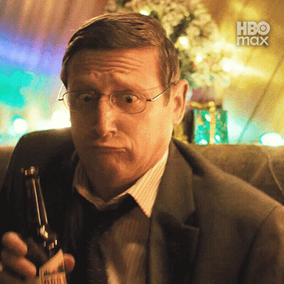 A Man In A Suit And Tie Is Holding A Bottle Of Beer With A Hbo Max Logo In The Background GIF