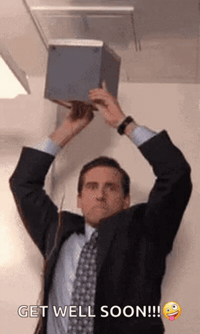 A Man In A Suit And Tie Is Holding A Box In His Hands Over His Head . GIF
