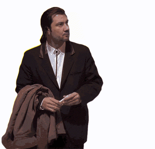 A Man In A Suit And Tie Is Holding A Brown Jacket Over His Shoulder GIF