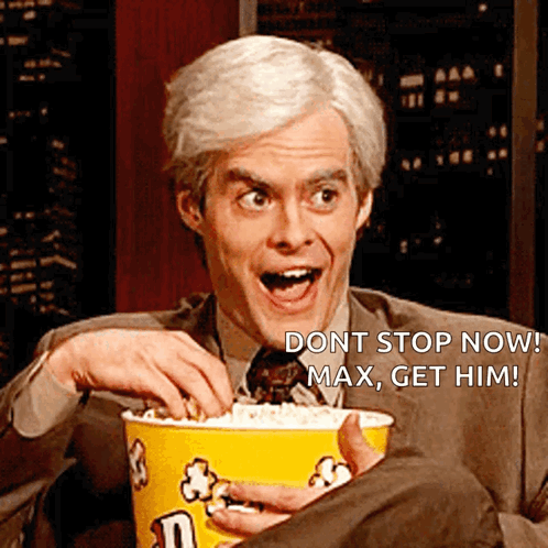 A Man In A Suit And Tie Is Holding A Bucket Of Popcorn And Says " Dont Stop Now " GIF