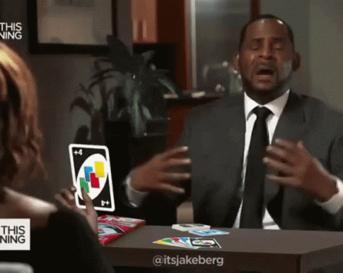 A Man In A Suit And Tie Is Holding A Card With The Number 4 On It GIF