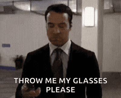 A Man In A Suit And Tie Is Holding A Cell Phone And Asking To Throw Me My Glasses Please . GIF