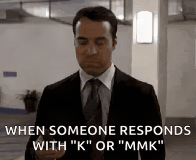 A Man In A Suit And Tie Is Holding A Cell Phone In A Parking Garage . GIF