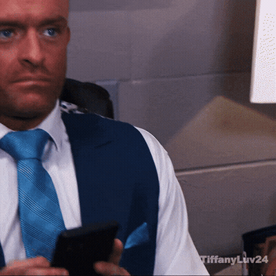 A Man In A Suit And Tie Is Holding A Cell Phone With Tiffany Liv24 Written On The Bottom GIF