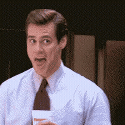 A Man In A Suit And Tie Is Holding A Cup And Making A Funny Face GIF