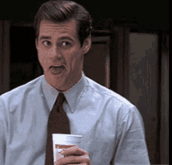 A Man In A Suit And Tie Is Holding A Cup Of Coffee GIF