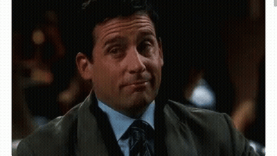 A Man In A Suit And Tie Is Holding A Drink In His Hand And Making A Funny Face . GIF
