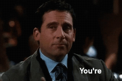 A Man In A Suit And Tie Is Holding A Drink In His Hand And The Word Welcome Is Behind Him GIF
