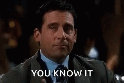 A Man In A Suit And Tie Is Holding A Drink In His Hand . GIF