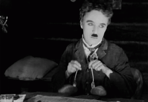 A Man In A Suit And Tie Is Holding A Fork In His Mouth GIF