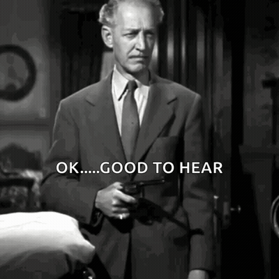 A Man In A Suit And Tie Is Holding A Gun And Says " Ok Good To Hear " GIF