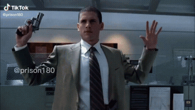 A Man In A Suit And Tie Is Holding A Gun In His Right Hand .. GIF