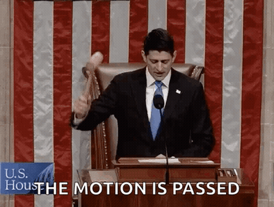 A Man In A Suit And Tie Is Holding A Hammer In Front Of A Podium And Says " The Motion Is Passed " GIF