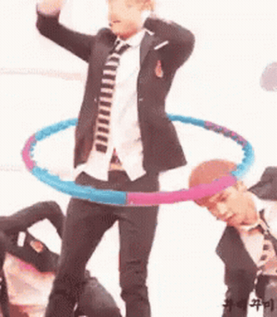 A Man In A Suit And Tie Is Holding A Hula Hoop Around His Waist . GIF
