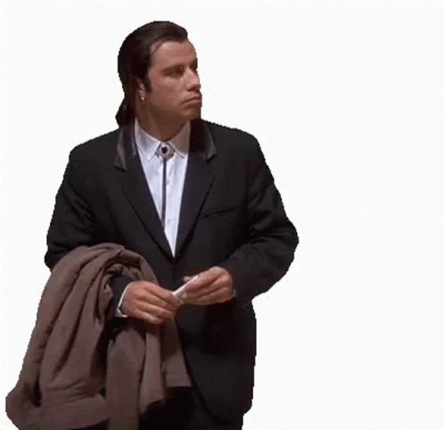 A Man In A Suit And Tie Is Holding A Jacket Over His Shoulder GIF
