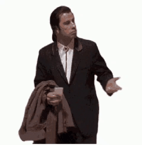 A Man In A Suit And Tie Is Holding A Jacket Over His Shoulders . GIF