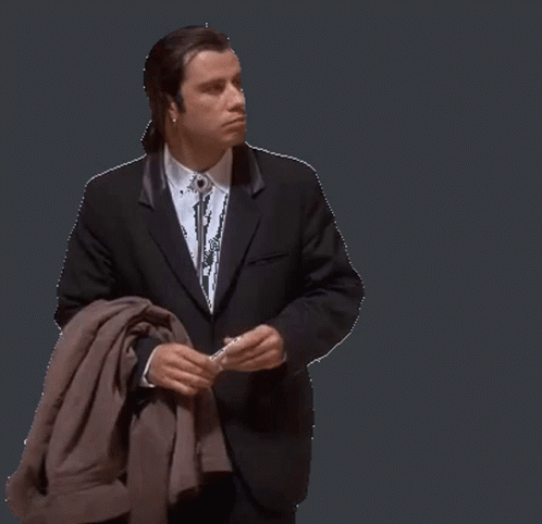 A Man In A Suit And Tie Is Holding A Jacket GIF