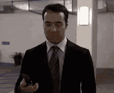 A Man In A Suit And Tie Is Holding A Knife In His Hand GIF