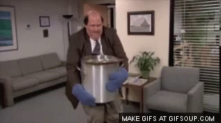 A Man In A Suit And Tie Is Holding A Large Pot In A Room . GIF
