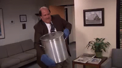 A Man In A Suit And Tie Is Holding A Large Pot . GIF