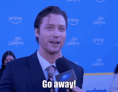 A Man In A Suit And Tie Is Holding A Microphone And Saying Go Away GIF