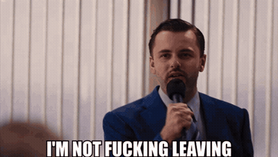 A Man In A Suit And Tie Is Holding A Microphone And Says I 'M Not Fucking Leaving GIF