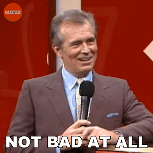 A Man In A Suit And Tie Is Holding A Microphone And Says Not Bad At All . GIF