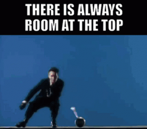 A Man In A Suit And Tie Is Holding A Microphone In Front Of A Yellow Background That Says There Is Always Room At The To GIF