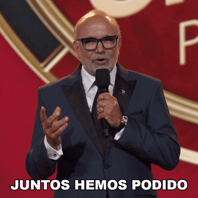 A Man In A Suit And Tie Is Holding A Microphone With The Words Juntos Hemos Podido Below Him GIF