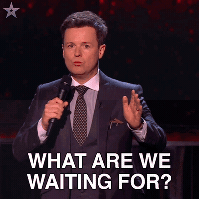A Man In A Suit And Tie Is Holding A Microphone With The Words Let 'S Get Going Below Him GIF