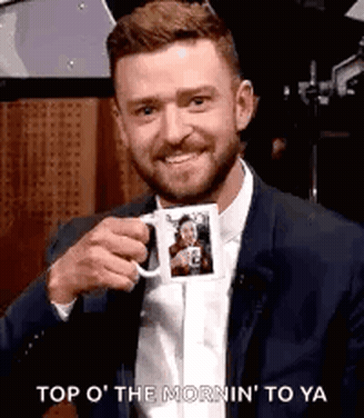 A Man In A Suit And Tie Is Holding A Mug With A Picture Of Him On It . GIF