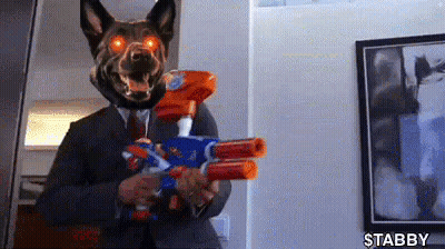 A Man In A Suit And Tie Is Holding A Nerf Gun . GIF