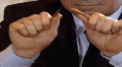 A Man In A Suit And Tie Is Holding A Pen Between His Fingers . GIF