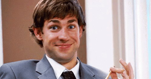 A Man In A Suit And Tie Is Holding A Pencil In His Hand And Smiling . GIF
