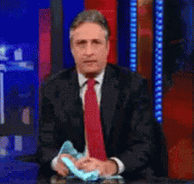 A Man In A Suit And Tie Is Holding A Piece Of Paper GIF